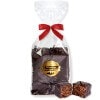 Three chocolate-covered Nuremberg Elisen gingerbread treats in a gift bag with a red bow; one piece has been cut.