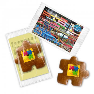 Puzzleteil aus Lebkuchen mit Logo, mit Werbekarte im Flowpack